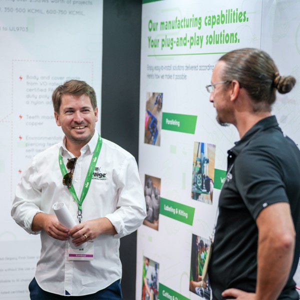 Two Paige representatives exchange a handshake at a tradeshow event.