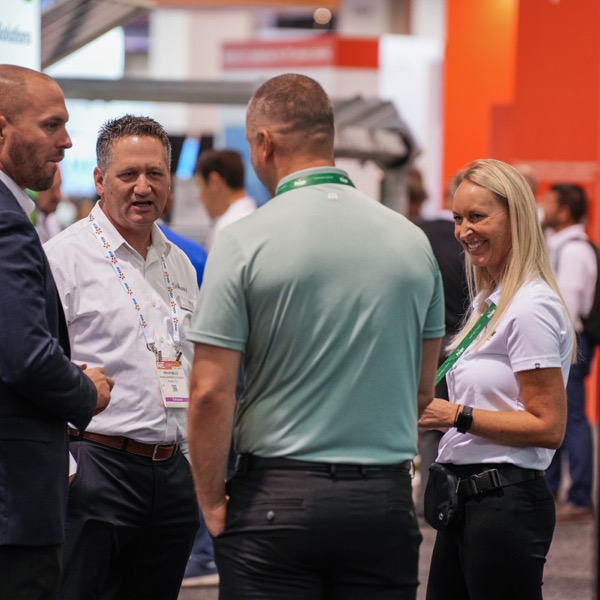 Candid photo of tradeshow attendees engage in conversation.